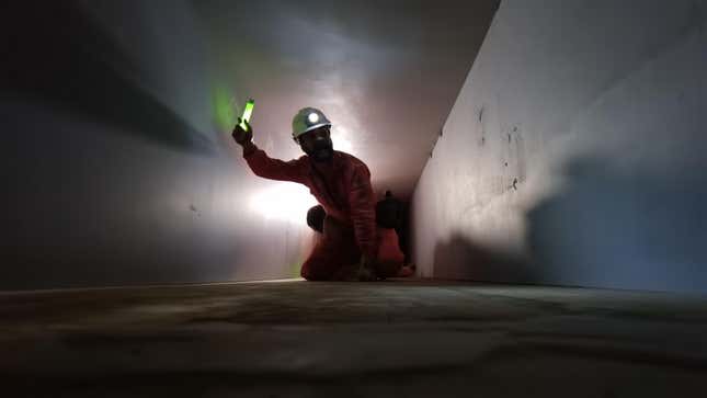 Ein Mann mit Helm hält einen Leuchtstab in einem Tunnel